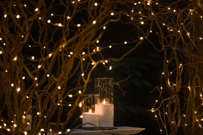 les-vases-hauts-avec-des-bougies-blanches-se-trouvent-sous-des-branches-brillantes.jpg ©v.ivash - Freepik