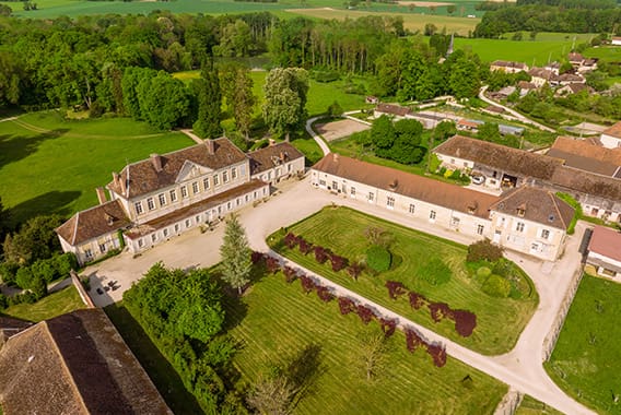 Château de Brantigny 16 - © Studio OG Vue aérienne du château de Brantigny entouré de jardins et de bâtiments en pierre, au cœur d’un paysage verdoyant de campagne dans l’Aube en Champagne