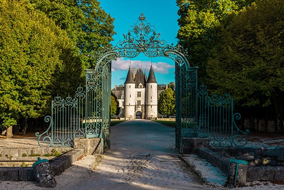 Château de Dampierre 11 - © Studio OG Entrée majestueuse d’un château avec portail en fer forgé et allée arborée menant au Château de Dampierre