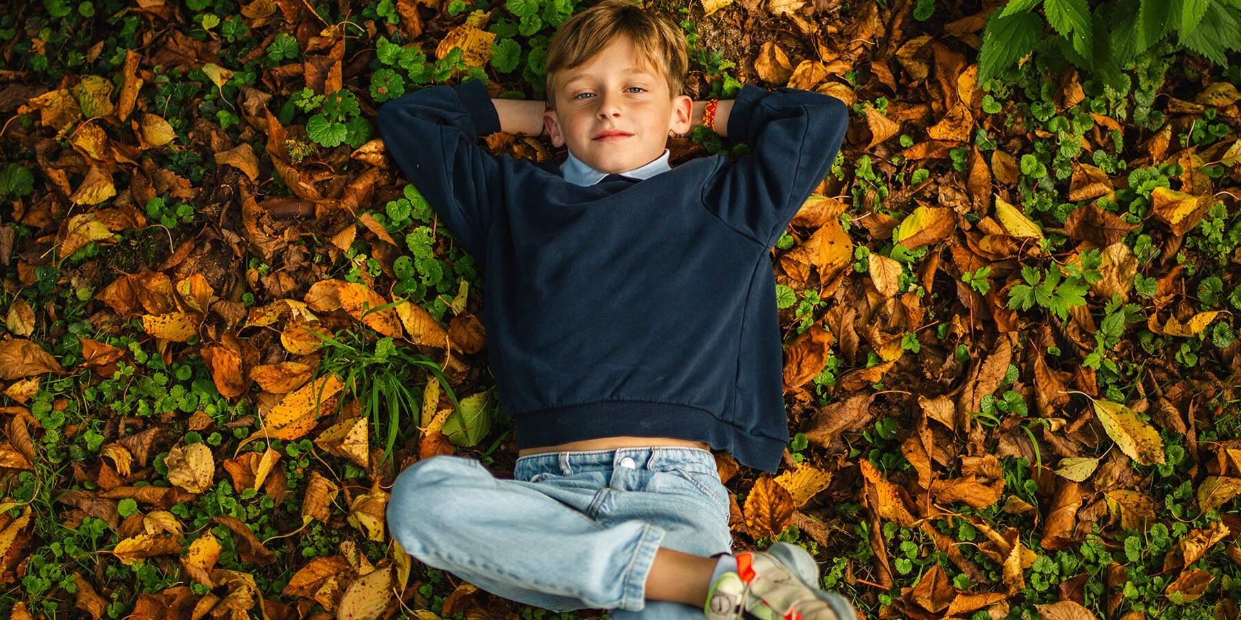 Jardin-d'automne-1---©-Prisma-Studio Enfant couché sur des feuilles d'automne